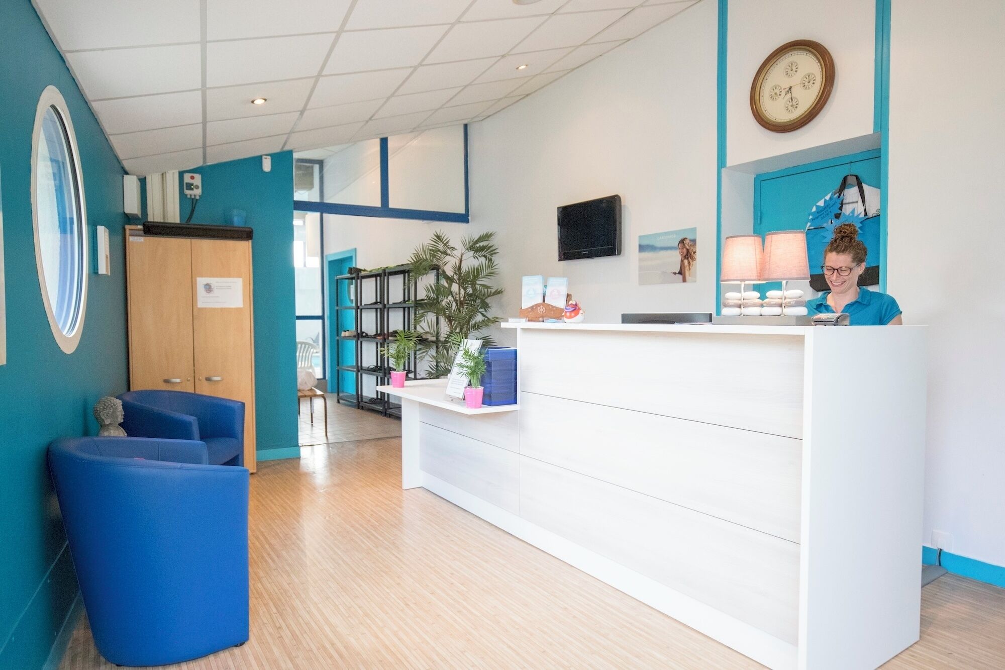 A reception area with a desk, chairs, a clock, and a plant.