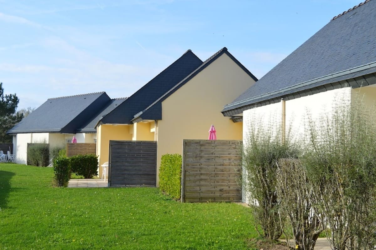 Een rij moderne huizen met schuine daken, een verzorgd gazon en een houten omheining.