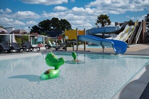 Una piscina con toboganes, sillas de descanso y un cielo despejado.