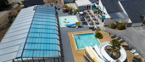 A large swimming pool with a slide, a separate smaller pool, and a covered area with lounge chairs.