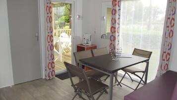 Une pièce comprenant une table et des chaises, un canapé violet et une porte donnant sur un espace extérieur avec une terrasse.