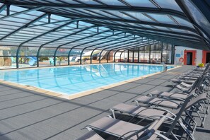 An indoor swimming pool with a glass ceiling, lounge chairs, and a view of the outside. - Club Vacances Bleues Keravel (Erdeven)
