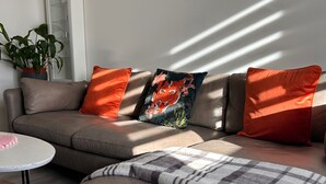 A modern living room with a sectional sofa, a small round table, and a decorative pillow with a fox design.