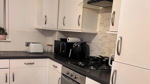 A kitchen with white cabinets, a black countertop, a stove, and a toaster.
