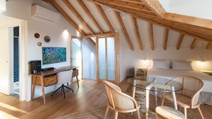 Une chambre à coucher de style loft moderne, avec des poutres en bois apparentes, une table à manger en verre et un lit confortable.