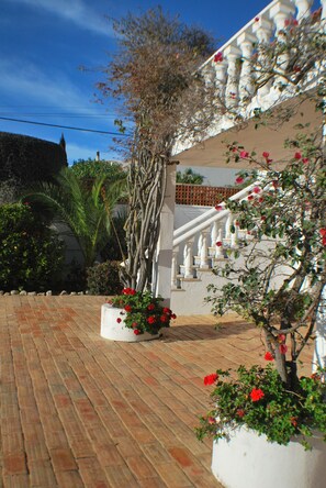 Stroll down the brick pathway to a charming white staircase with ornate details.