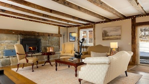A cozy living room with a stone fireplace, wooden beams, and comfortable seating.