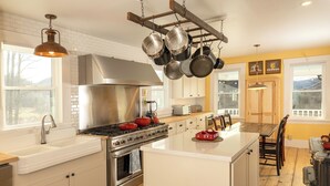 A kitchen with white cabinets, a stainless steel stove, and hanging pots.