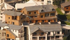 Un quartier résidentiel composé d’immeubles à plusieurs étages, dont certains sont dotés de balcons apparents et de panneaux solaires.
