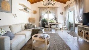 Un salon moderne avec un plafond en bois, une table basse ronde, un canapé et un meuble pour la télévision.