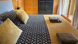 Ein Zimmer in einer Holzhütte mit einem Bett, einem Schreibtisch und einem Kleiderschrank.