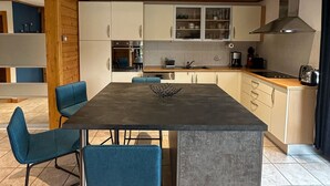 Eine moderne Küche mit einer Kochinsel, blauen Stühlen und Holzausbau.
