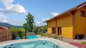Ein Garten mit Whirlpool, einem Holzhaus und Blick auf die Berge.