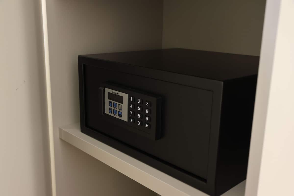 A black safe with a keypad on a white shelf.