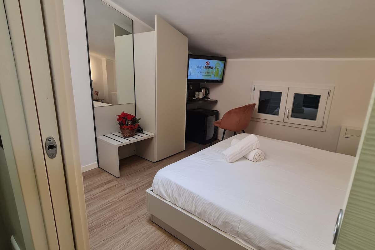 A bedroom with a bed, a TV, a desk, and a wardrobe.