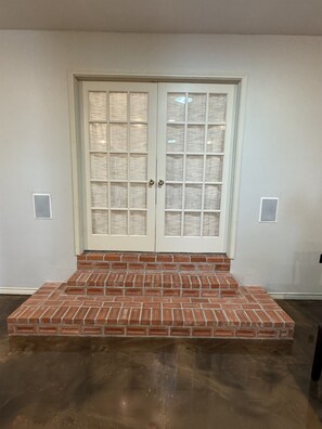 A double door with a glass panel design, a brick base, and a light-colored wall.