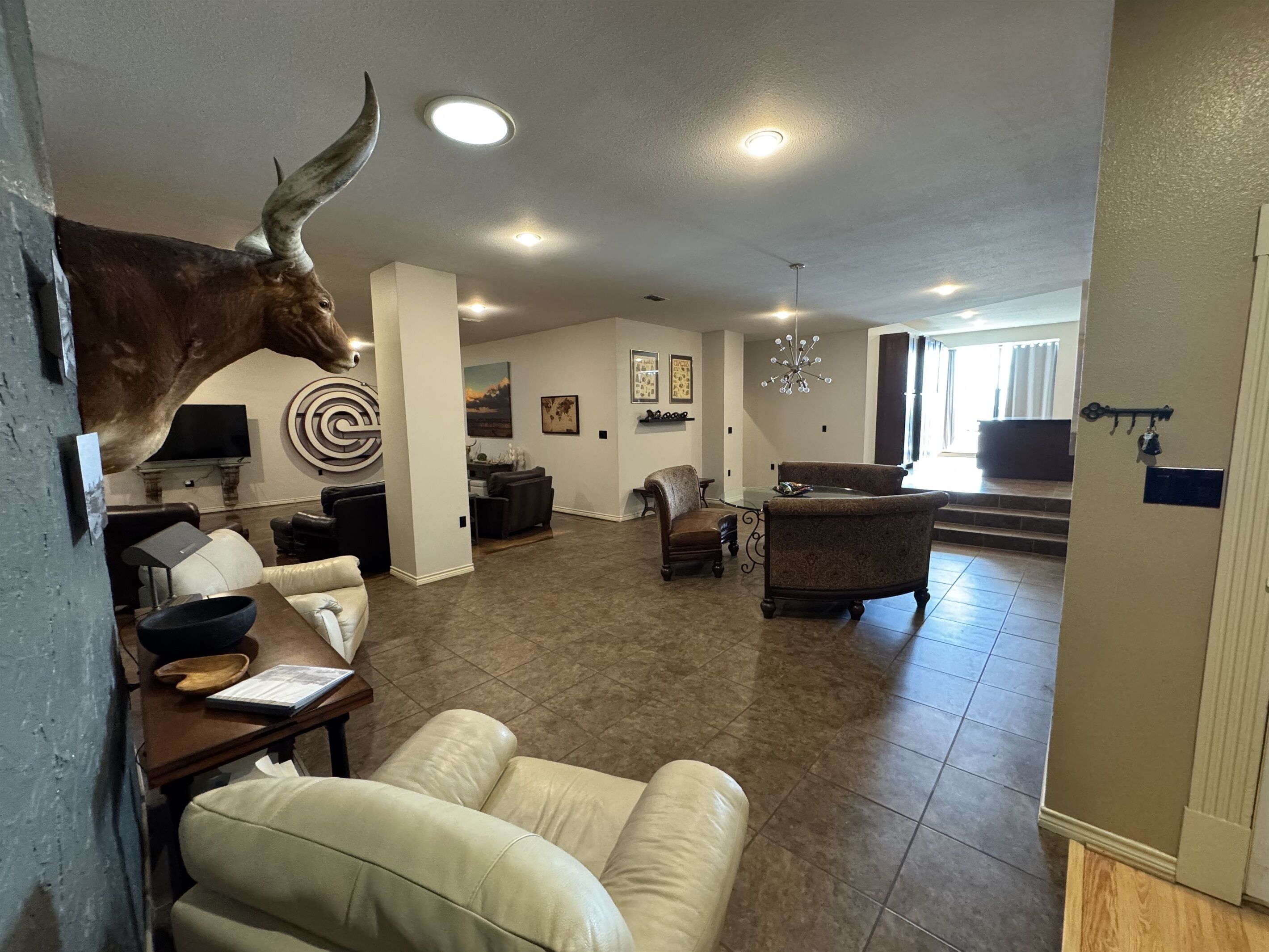 A spacious living room with a mounted bull head, a fireplace, a dining area, and a kitchen.