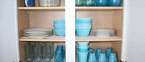 A cabinet with shelves containing various kitchenware.