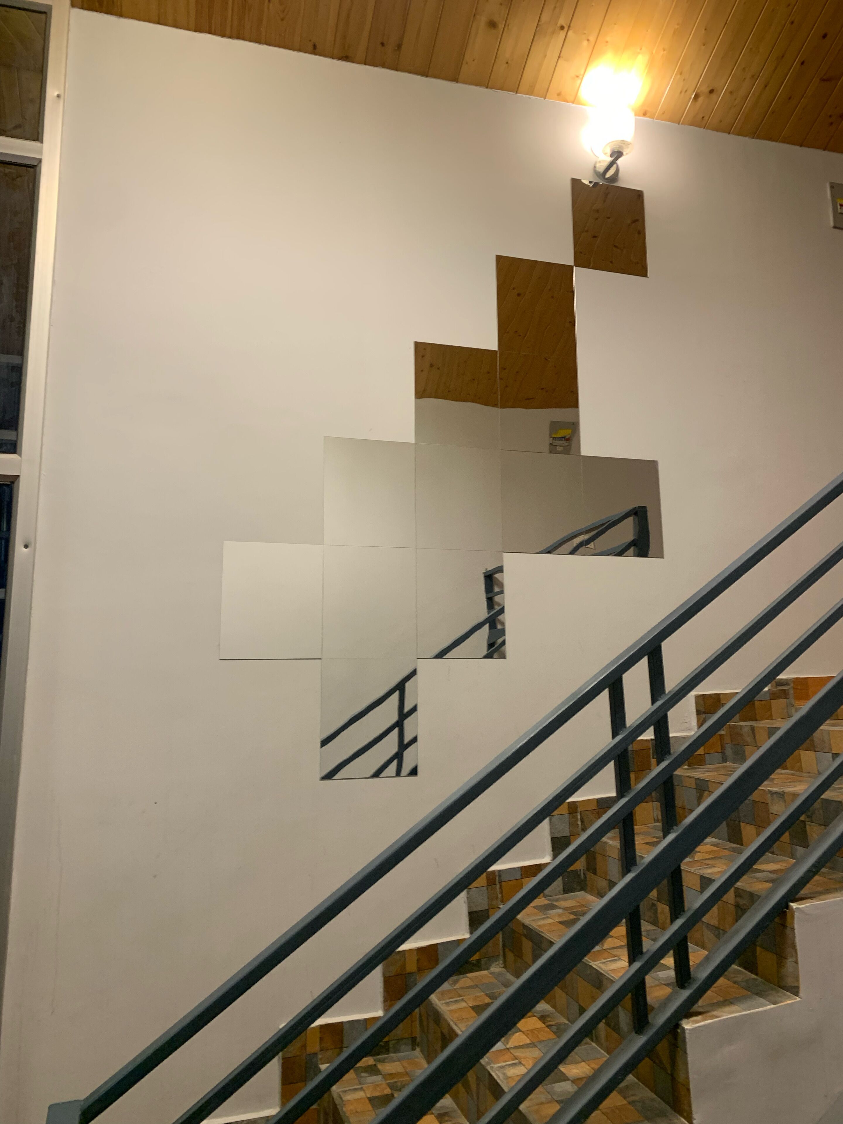 Un escalier au design moderne, agrémenté d’un motif géométrique sur le mur et d’une rampe en métal.