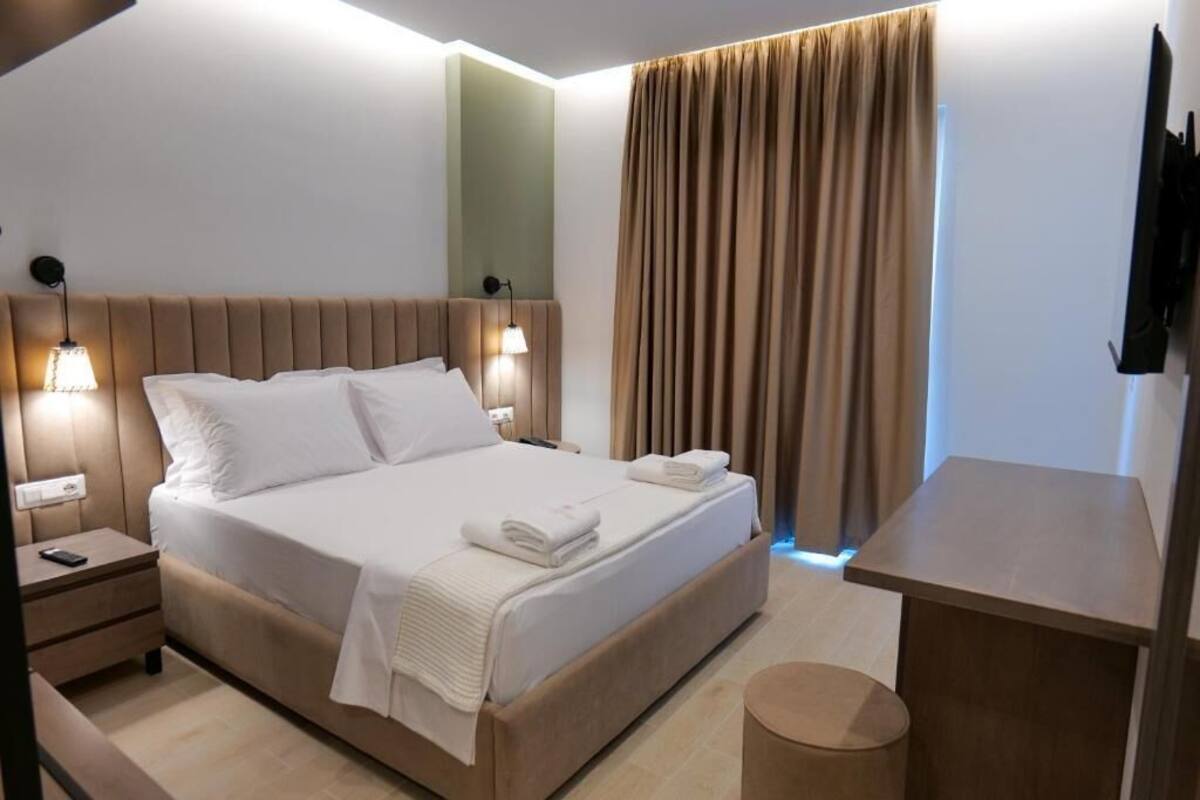Una habitación de hotel moderna con una cama grande, lámparas de noche, un televisor de pantalla plana y una mesita.