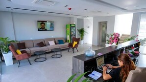 A modern office space with a reception desk, a sofa set, and a laptop on the desk. - Nerium Hotel (Ksamil)