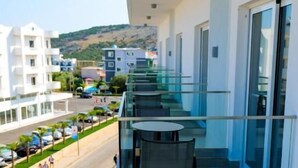 A modern building with a glass balcony overlooking a street. - Nerium Hotel (Ksamil)