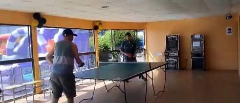 A ping pong table in a room with yellow walls and a large window.