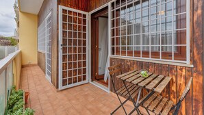 Un balcon doté d’une façade en bois, d’une porte-fenêtre coulissante et d’une petite table en bois.