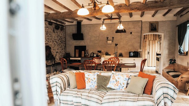 A cozy living room with a striped sofa, wooden chairs, and a dining table. - Guest rooms : La Cavalière - LA SOURCE DE NOS RACINES - CORPS DE FERME - AVESNOIS (Beaufort)