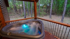 A hot tub on a wooden deck with a forest view. - As You Wish Cabin in a breathtaking one-bedroom honeymoon cabin that is the perfect place to make lasting memories with each other. (Broke Bow)