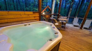 Un jacuzzi en una terraza de madera con vista a un bosque.