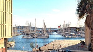 Un port esportiu amb vaixells amarrats, una passarel·la per a vianants i vehicles estacionats al costat.