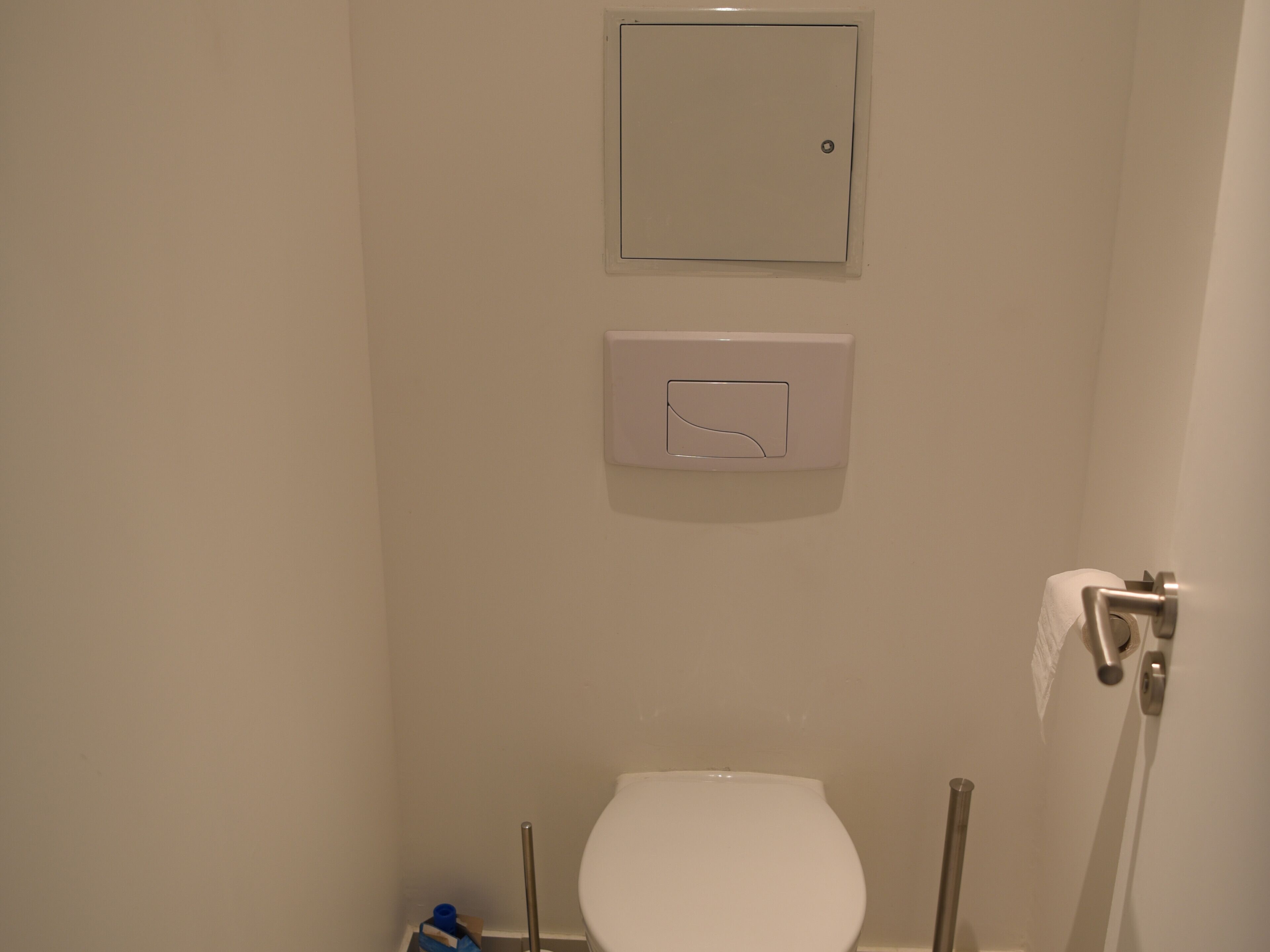 A bathroom with a toilet, a hand dryer, and a towel rack.