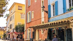 A street with colorful buildings, outdoor seating, and a café.