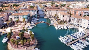 A marina with boats docked, a bridge, and buildings with balconies.
