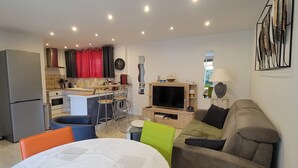 A compact living space with a kitchenette, a dining area, and a seating area with a sofa and chairs.