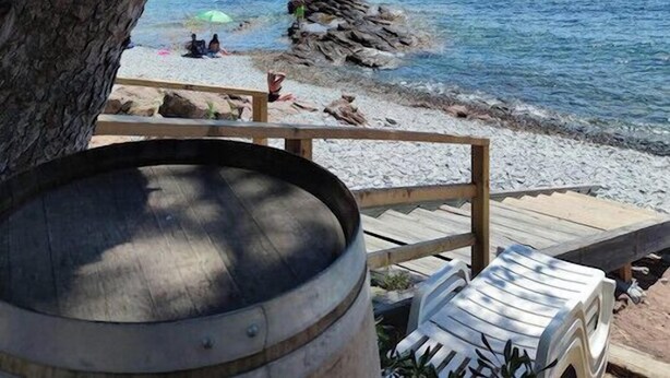 A beach with boats, a wooden deck, and a barrel.