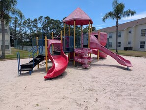 Ein Spielplatz mit einer roten Rutsche und einer Kletterkonstruktion.