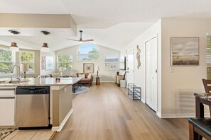 A spacious kitchen with a central island, a dining area with a round table, and a living room with a sofa and a coffee table.
