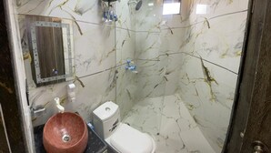 A bathroom with a marble wall, a sink with a bowl, a toilet, and a shower. - BEST HOME STAY IN VRINDAVAN (Vrindavan)
