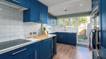 A modern kitchen with blue cabinets, white tiles, and a wooden countertop.