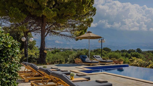Ein Poolbereich mit Liegestühlen, einem kleinen Pool und Blick auf die Landschaft.
