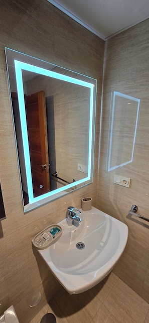 A bathroom with a large mirror, a white sink, and a towel rack. - Ola Rosaleda (Málaga)
