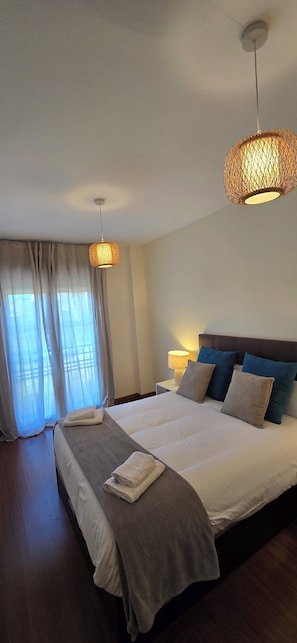 A hotel room with a large bed, two bedside lamps, and a window with curtains. - Ola Rosaleda (Málaga)
