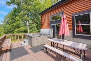 A wooden deck with a hot tub, picnic tables, and a covered umbrella. - Ridgeview Retreat | Hocking Hills, Hot Tub, Sauna (South Bloomingville)