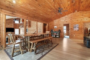 A spacious wooden cabin with a long dining table, a ceiling fan, and a fireplace. - Ridgeview Retreat | Hocking Hills, Hot Tub, Sauna (South Bloomingville)