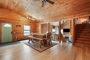 A wooden cabin interior with a dining area, a fireplace, and a staircase. - Ridgeview Retreat | Hocking Hills, Hot Tub, Sauna (South Bloomingville)