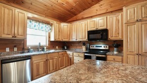 A kitchen with wooden cabinets, granite countertops, a stainless steel dishwasher, a microwave, and an oven.