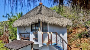 Una cabaña con techo de paja, una escalera de madera y una pequeña mesa.
