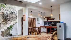 Una cocina con pared de piedra, muebles de madera y lámparas colgantes.